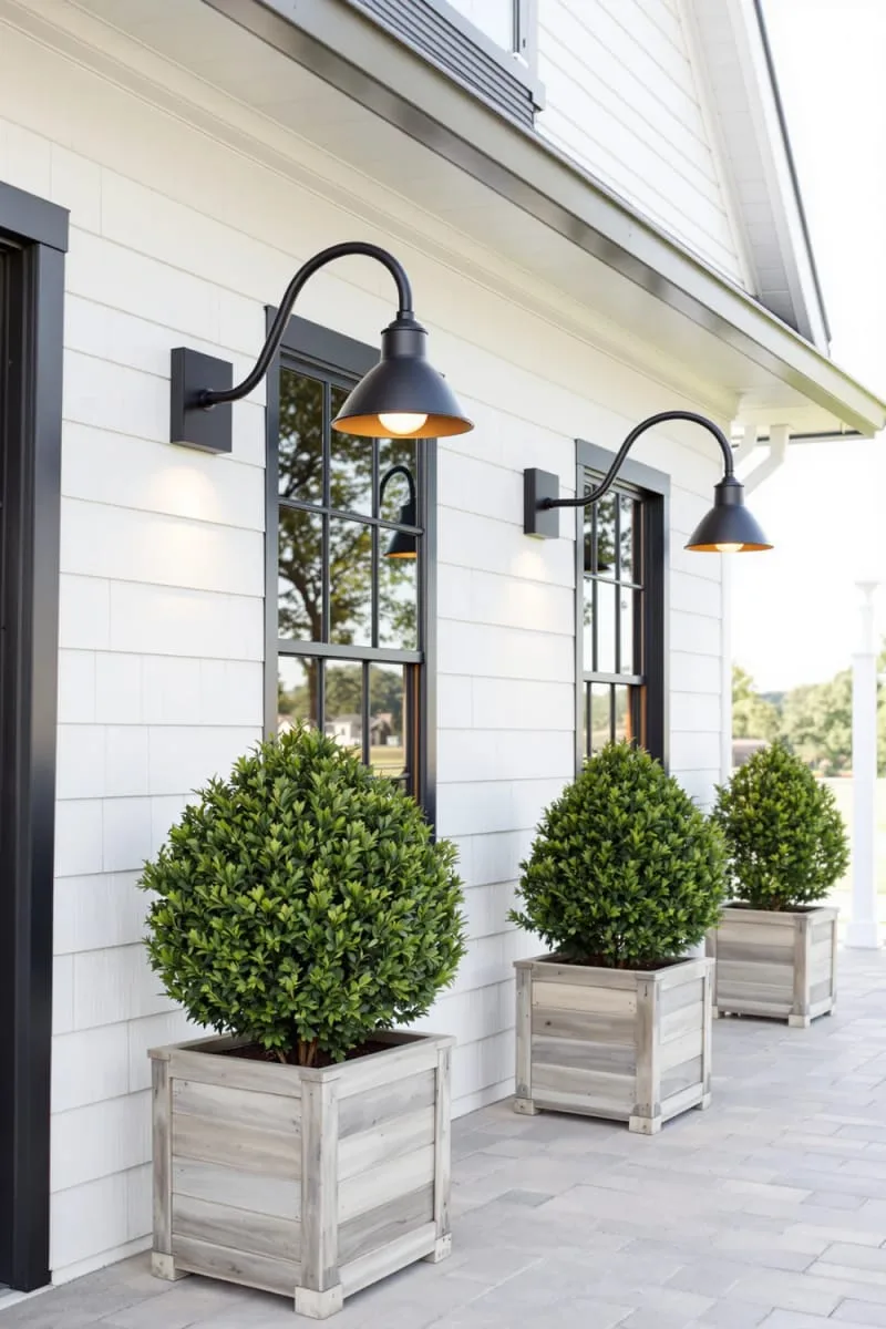 classic farmhouse exterior lights paired with lush boxwood planters 1