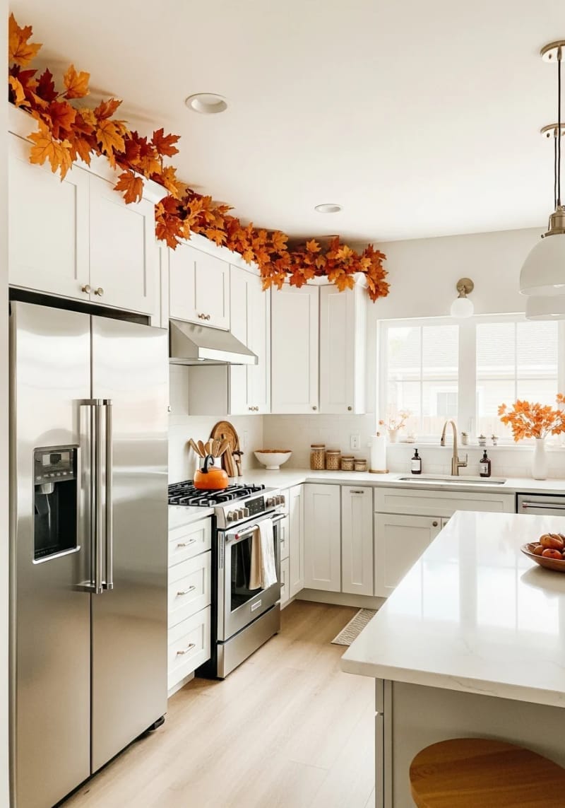 faux autumn leaves draped across kitchen cabinets for a cozy fall vibe 1