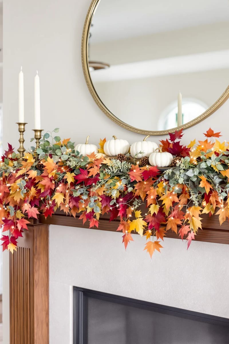 mantelpiece draped in cascading faux maple leaves and white pumpkins 1