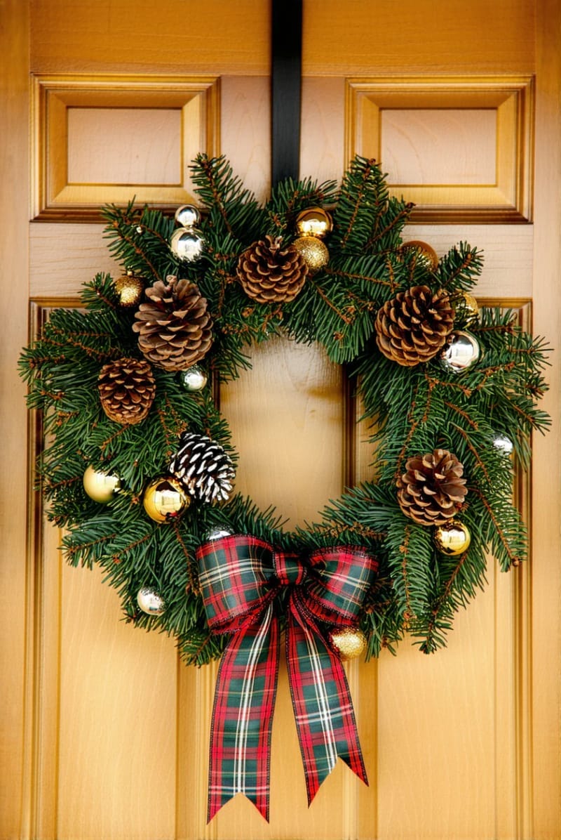 plaid and pinecone wreath with metallic baubles on a wooden front door 1