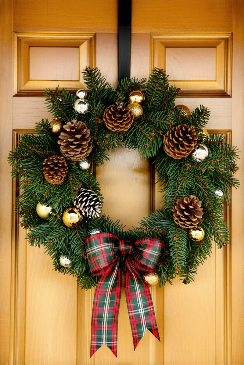 31 Trendy Christmas Decor Ideas for a Magical Home 6 plaid and pinecone wreath with metallic baubles on a wooden front door 1