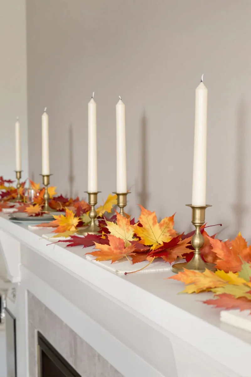 taper candles in antique brass holders with scattered maple leaves 1