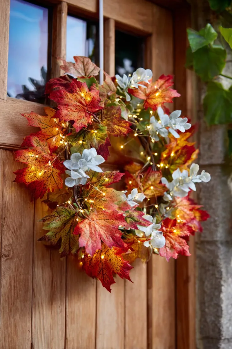wreath of maple leaves, eucalyptus, and twinkle fairy lights on front door 1