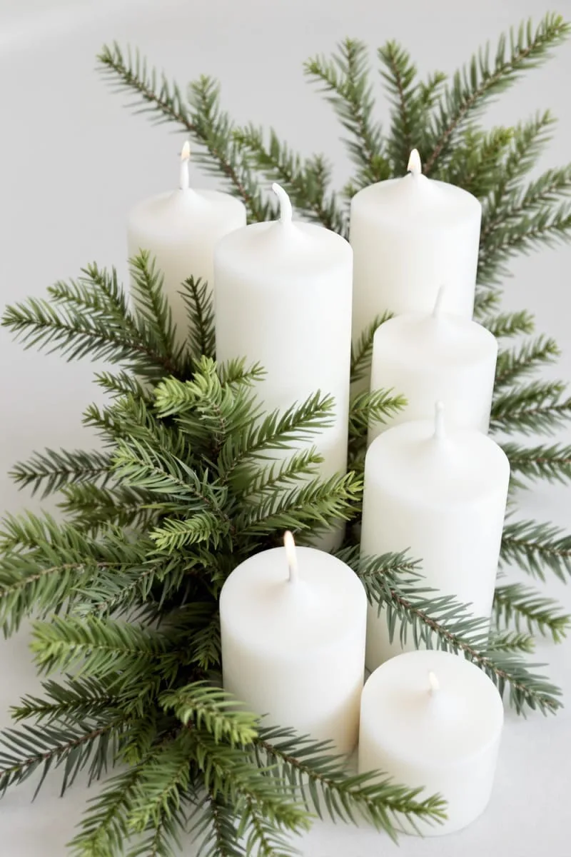 29 Simple Christmas Decor Ideas for a Beautiful Holiday Season 26 cluster of white pillar candles nestled in pine sprigs 1