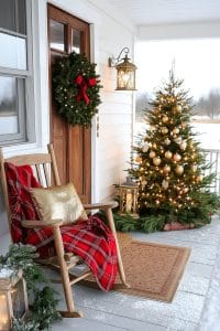 15 Dreamy Front Porch Christmas Trees to Try This Year 1 magical golden-lit tree beside a cozy wooden rocking chair 19