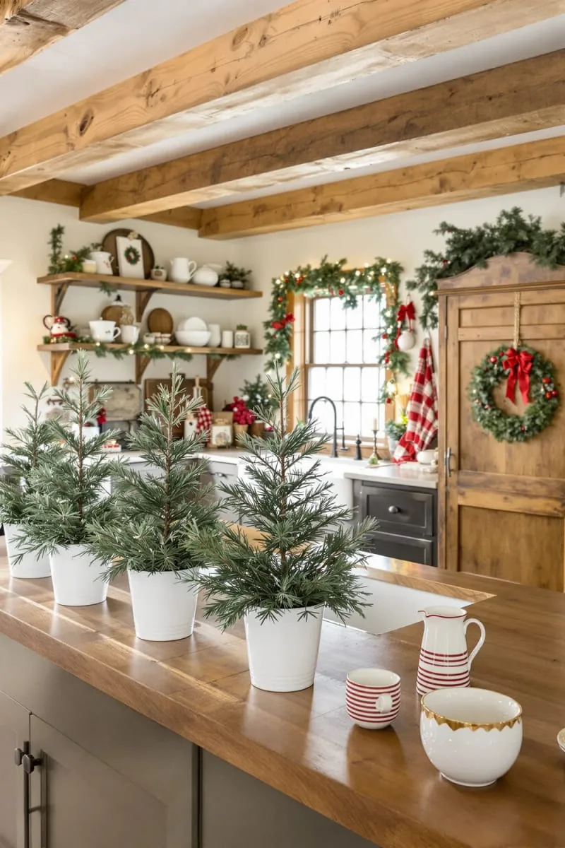 23 Christmas Countertop Decor Ideas Guests Can’t Stop Talking About 3 mini pine trees in white ceramic pots lined along the kitchen countertop 1