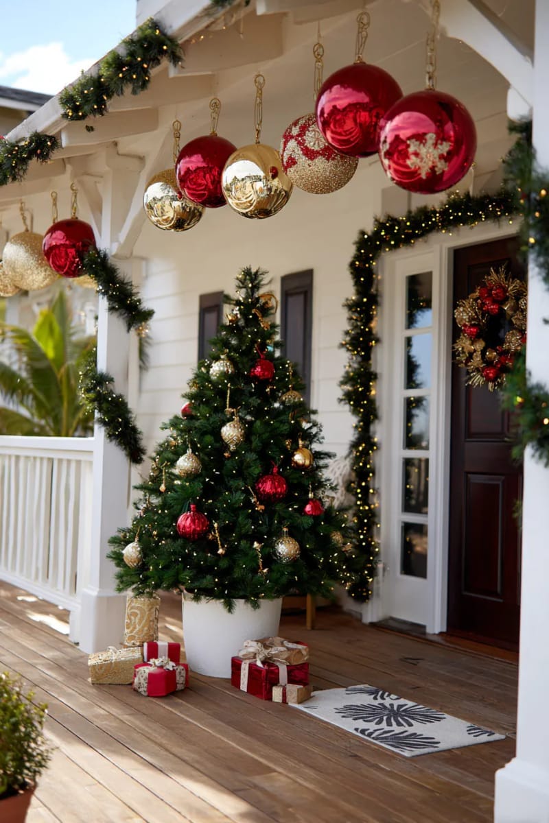 15 Dreamy Front Porch Christmas Trees to Try This Year 18 oversized hanging ornaments above porch with matching tree decorations below 1