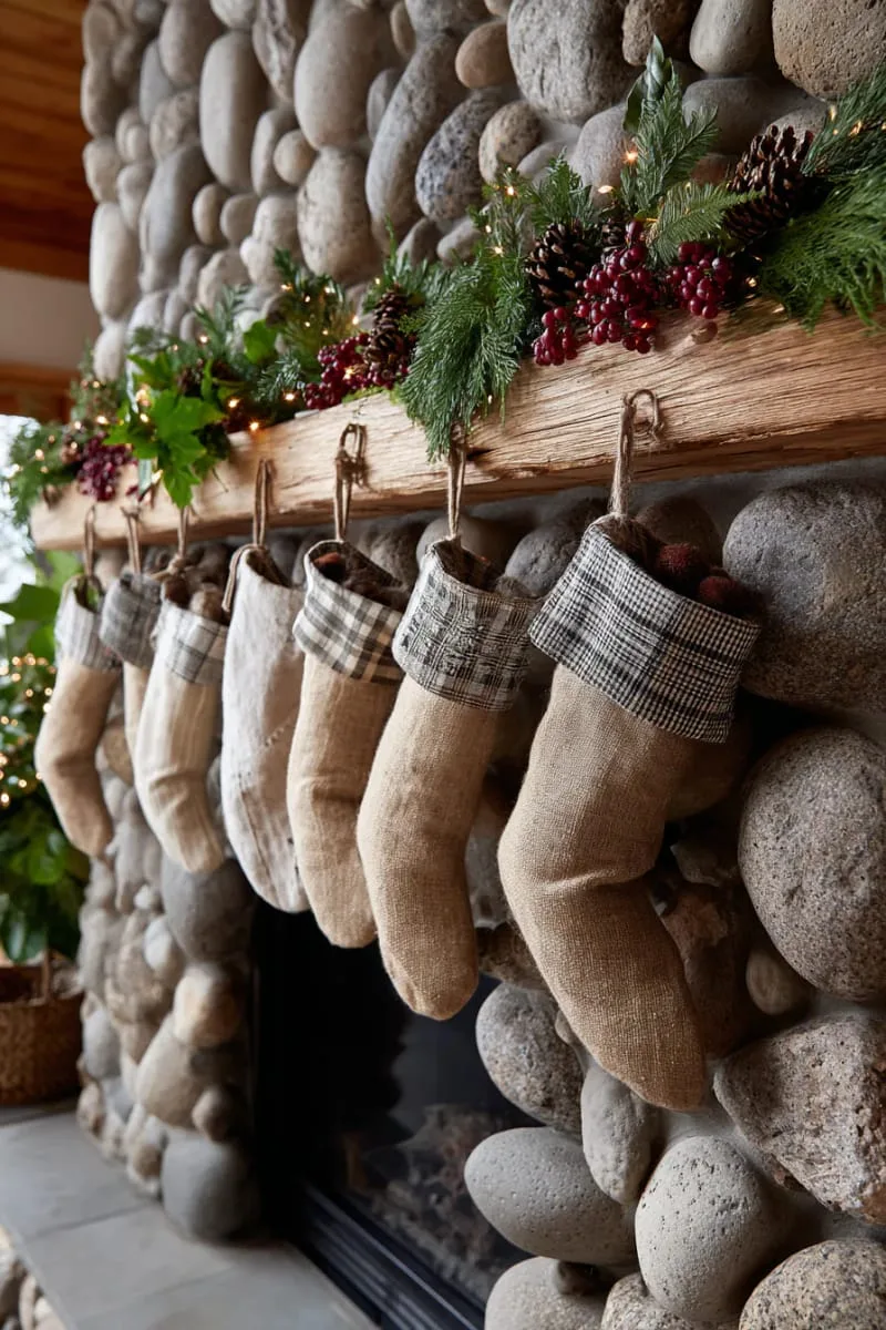 rustic burlap stockings and garland across a stone fireplace 1