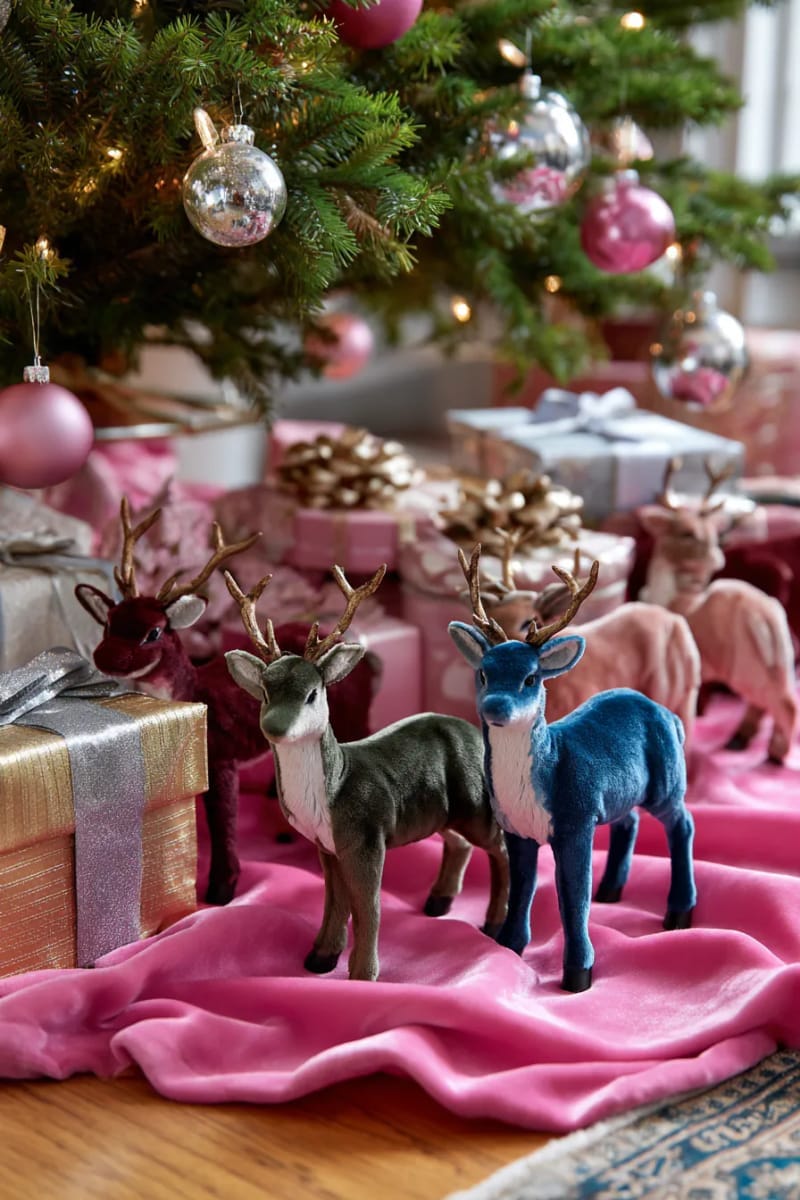 23 Kitsch Christmas Decor Ideas Full of Color, Whimsy, and Cheer 18 velvet reindeer figurines arranged under a neon pink tree skirt 1
