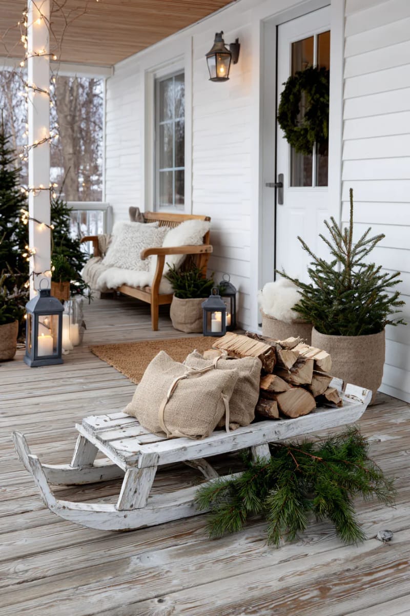 whitewashed wooden sled propped up with bundles of firewood and greenery. 1