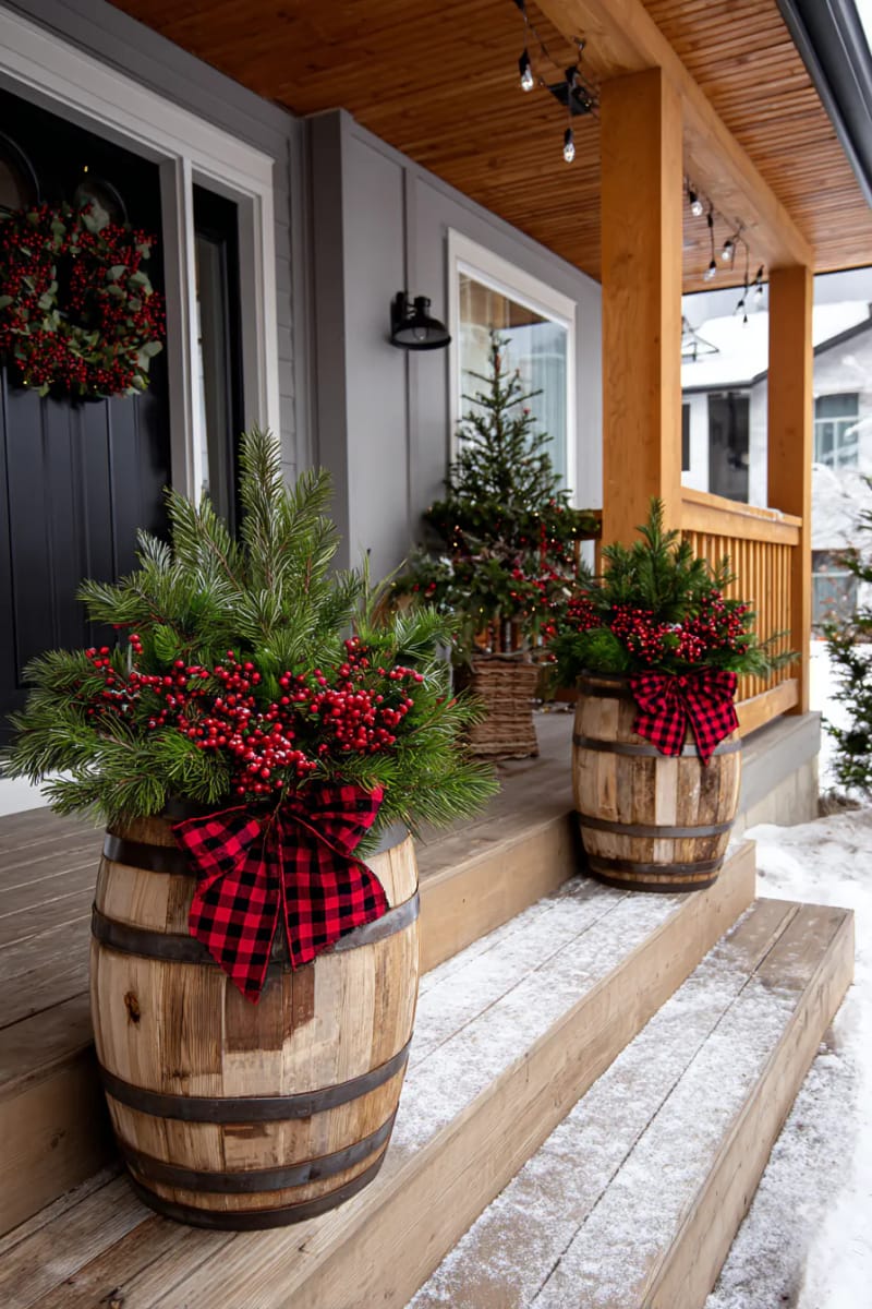 barrel planters overflowing with pine branches, red berries, and plaid ribbon bows 1