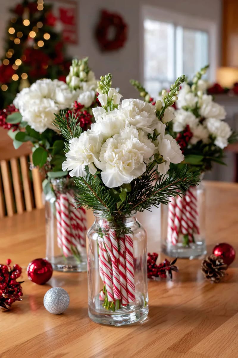 candy cane striped vases holding fresh white flowers and pine needles 1