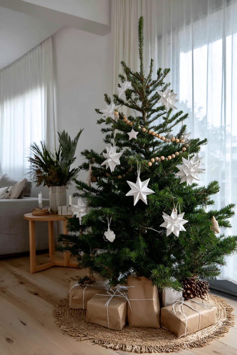 scandinavian style tree with white ornaments, paper stars, and natural wood garland 1