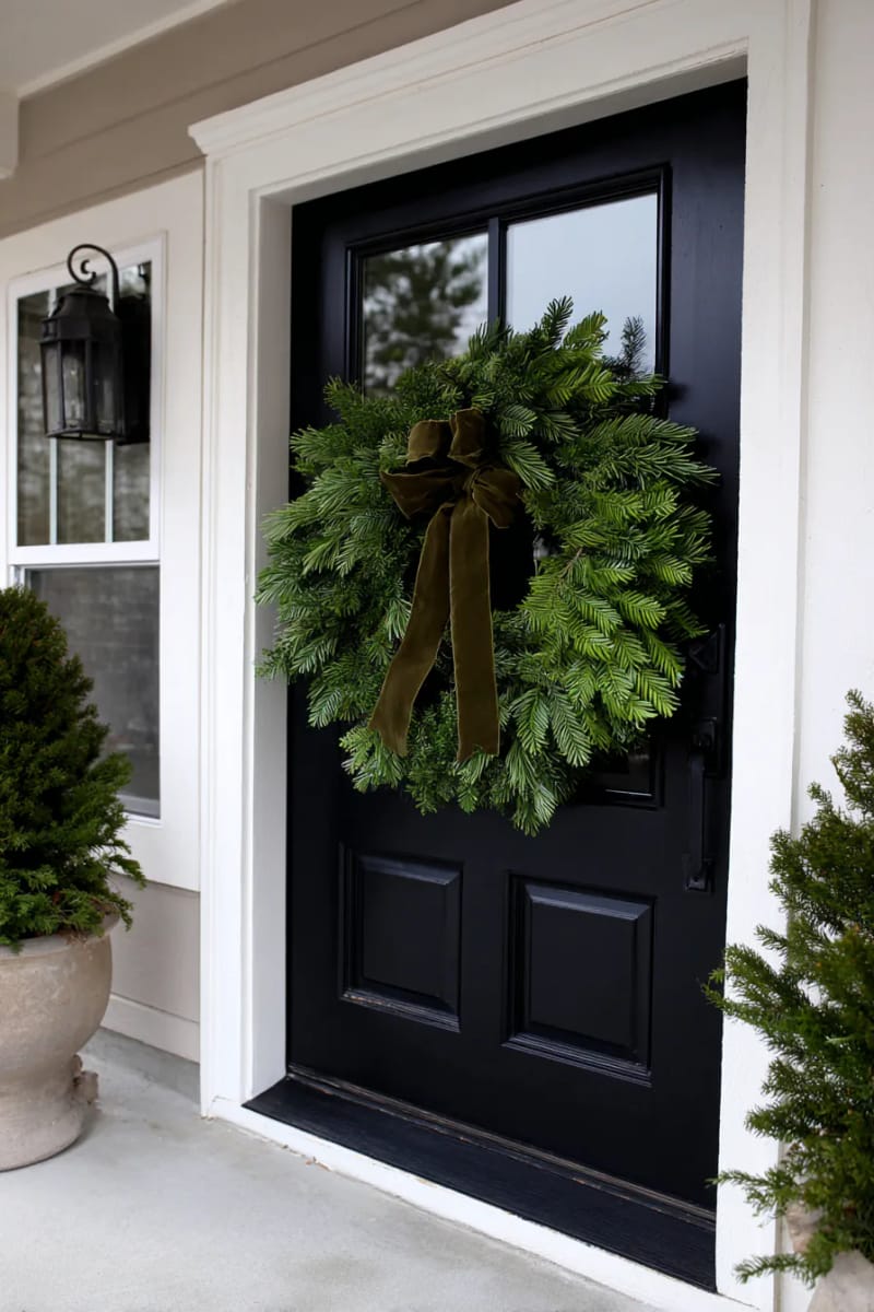 single pine wreath with velvet ribbon on a black front door 1