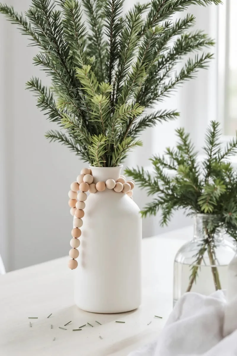 wooden bead garlands draped over pine branches in simple scandinavian vases 1
