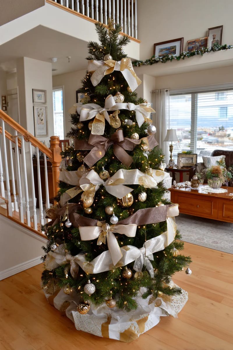wrap a christmas tree in alternating gold, bronze, and champagne ribbons. 1