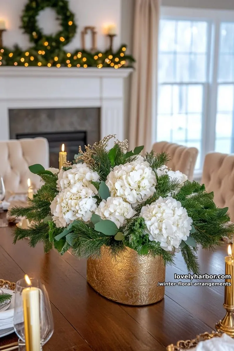 creamy white hydrangeas and cedar sprigs with gold candle centerpiece 1