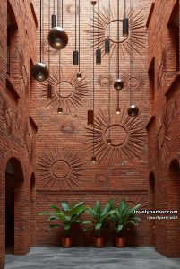 tall atrium with terracotta brick sunburst wall and modern pendant lights 3