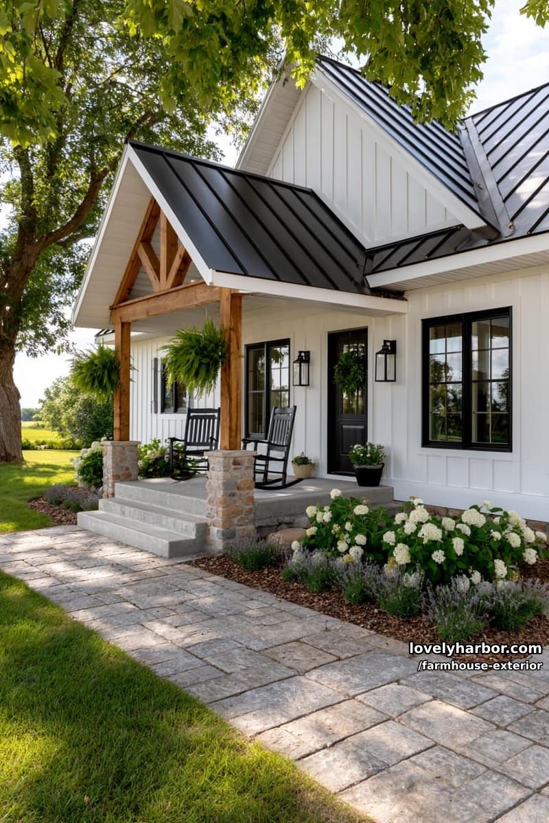 white farmhouse with black windows, gabled roof, and welcoming porch with greenery. 1