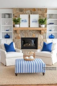 cream armchairs, striped ottoman, blue accents, and stone fireplace in coastal living room. 18