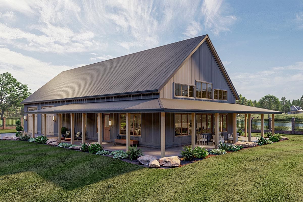 Exterior view of a 3-bedroom barndominium house plan featuring a massive wrap-around porch, vertical siding, large windows, and landscaped yard, illustrating the wrap around porch house plan concept.
