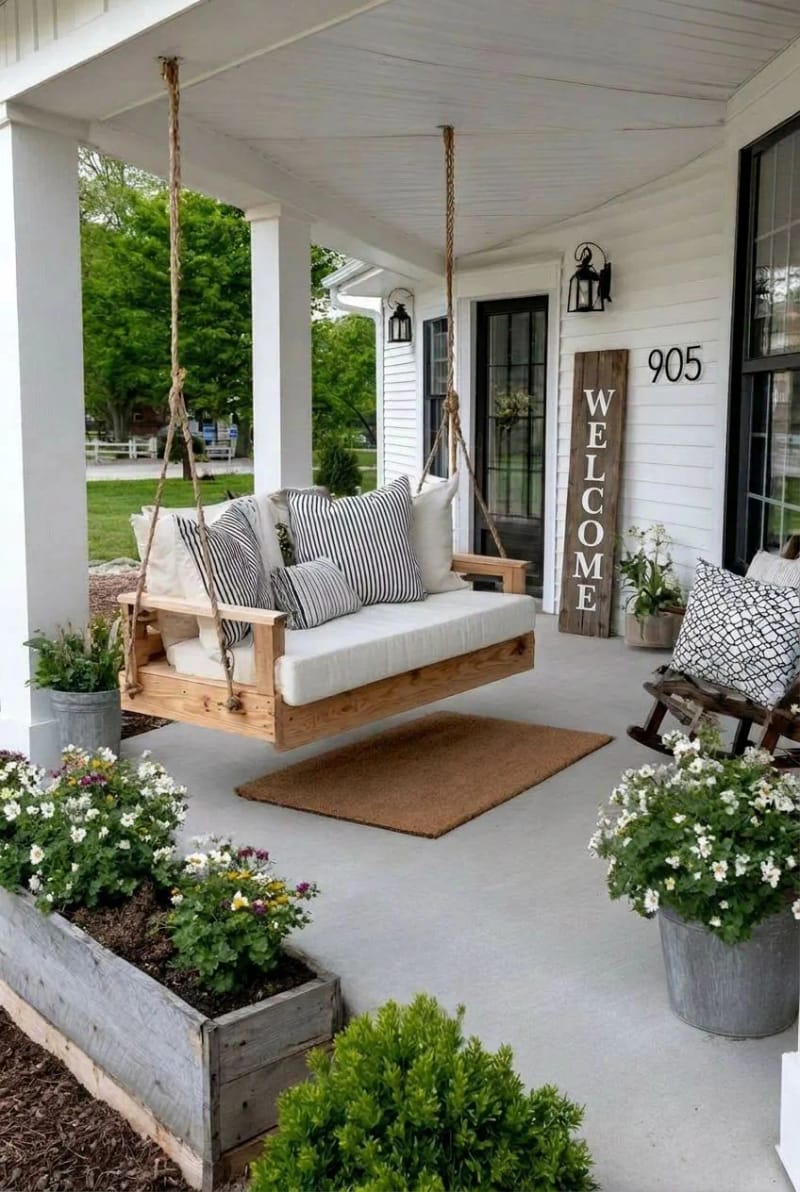 farmhouse porch with concrete floor, swing, planters, and "welcome" sign. 1
