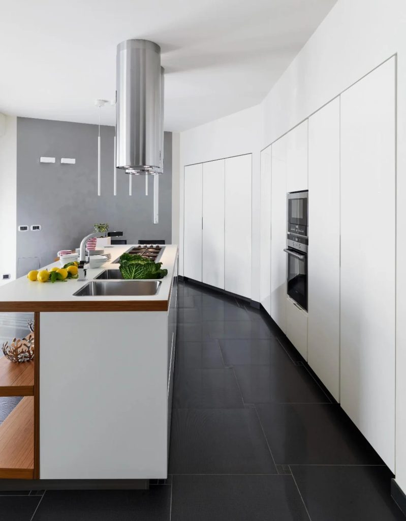 Minimalist kitchen featuring seamless white cabinetry, integrated appliances, a modern island with wood accents, and a stainless steel range hood, illustrating functional design for minimalist kitchen ideas that survive actual cooking