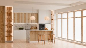 12 Japandi Kitchen Design Ideas That Survive Actual Cooking 7 A bright Japandi kitchen design featuring light wood accents, minimalist white cabinetry, marble countertops, two wooden stools at a central island, pendant lighting, and large windows allowing natural light to fill the space.