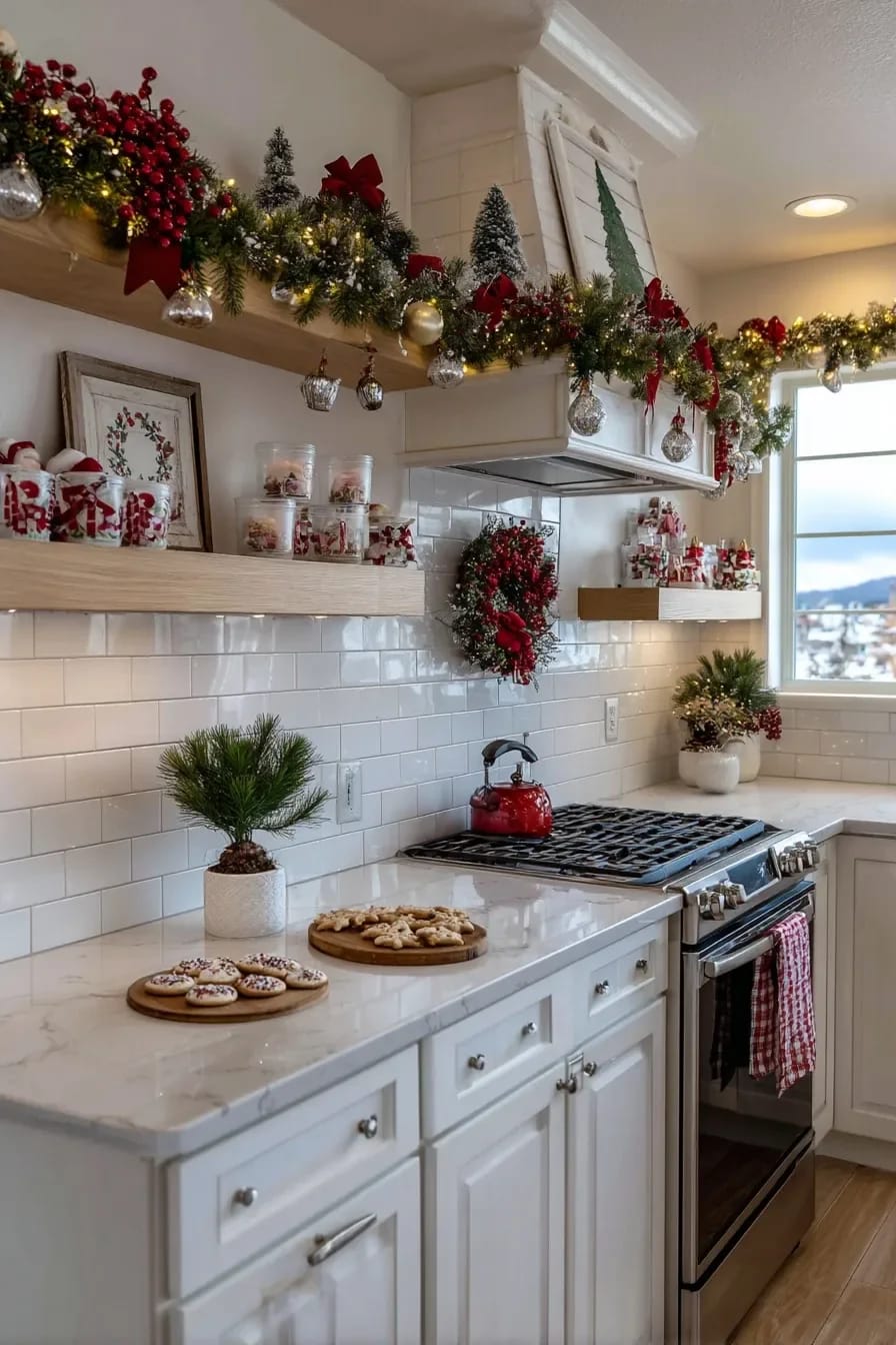 Christmas Kitchen Decor Ideas for a Kitchen You Still Have to Cook In 9 Bright kitchen decorated for Christmas with garland, red bows, ornaments, wreaths, and holiday treats on marble countertops, highlighting festive decor on vertical surfaces.