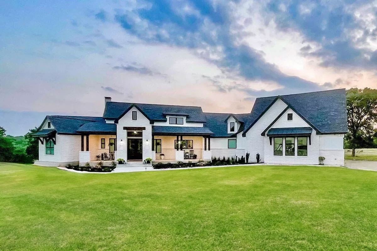 Modern farmhouse with white brick exterior, black trim, and covered front porch at dusk.
