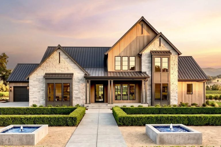 Modern farmhouse exterior with stone and wood siding, metal roof, and landscaped entry with fountains