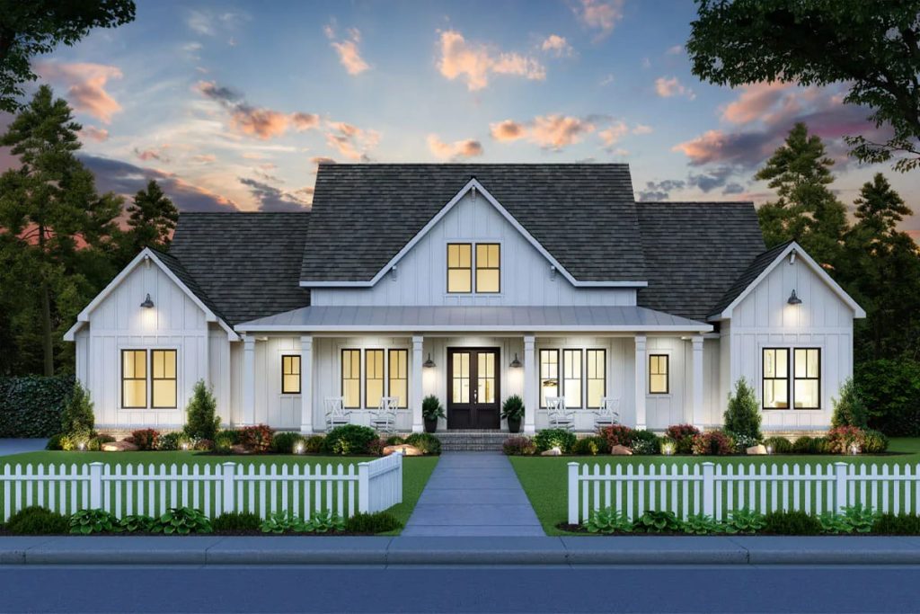 Modern farmhouse with white siding, large front porch, and picket fence at dusk