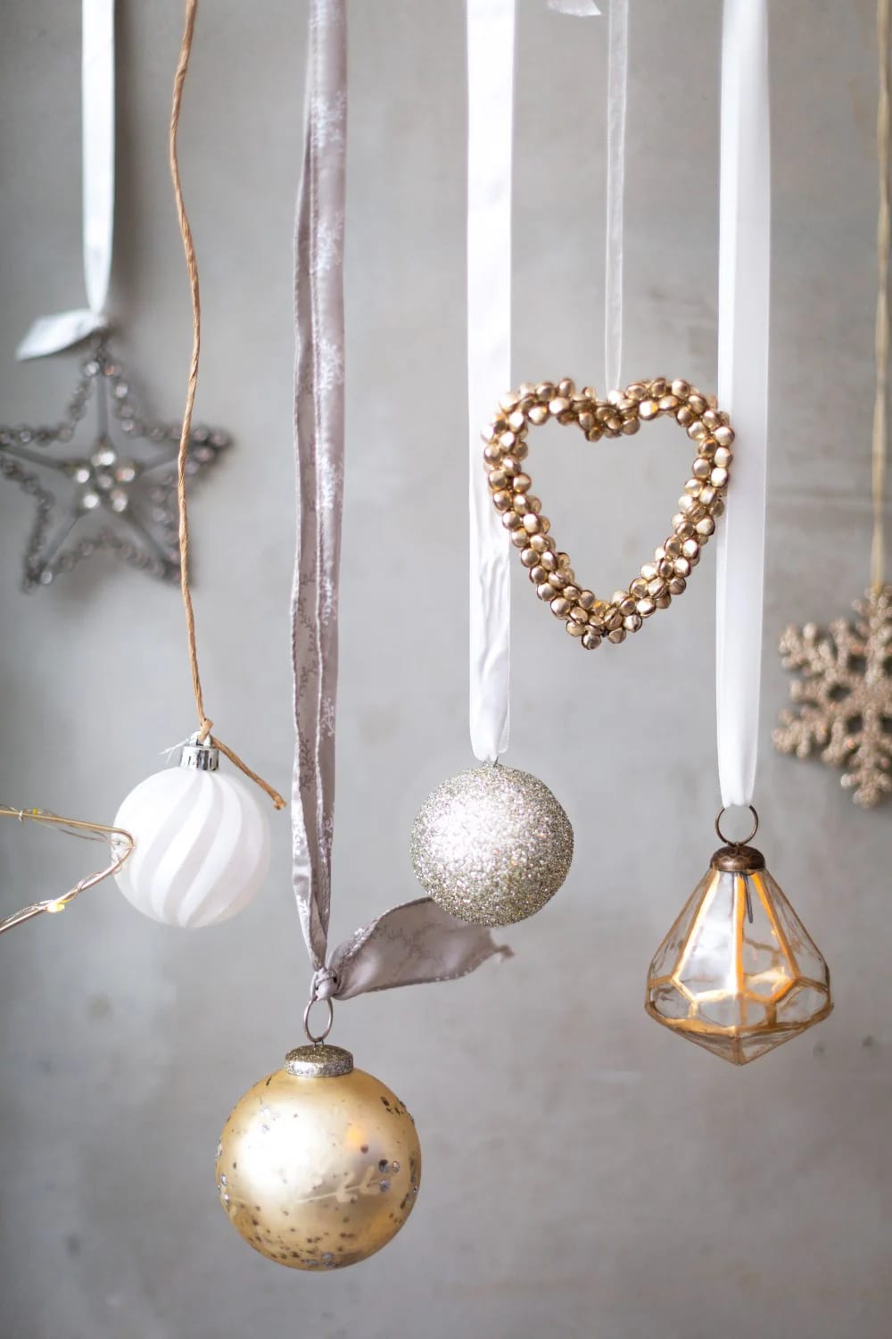 Assorted Christmas ornaments including stars, baubles, and a heart shape hanging from ribbons, illustrating ceiling decor ideas for narrow hallways and low ceilings.