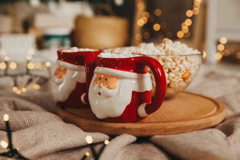 How to Display a Santa Mug Collection 1 Two Santa-shaped mugs filled with marshmallows on a wooden tray next to a bowl of popcorn, illustrating a festive way to display a Santa mug collection.