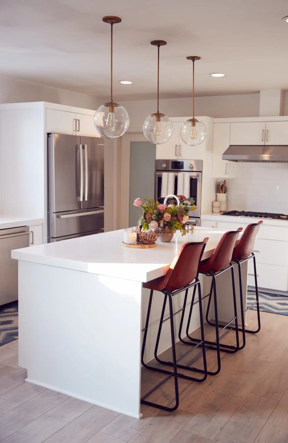 Kitchen Island With Dining Table: 11 Combinations That Actually Get Used 4 A spacious kitchen island with a 36-inch white countertop, four brown high-back dining chairs, pendant lights above, and a floral centerpiece, illustrating a kitchen island with dining table combination.