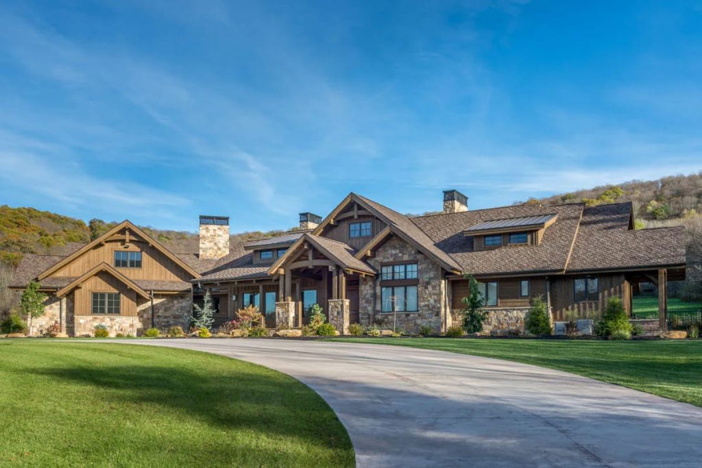 Rustic mountain-style home with stone and wood exterior, steep gables, and a large circular driveway.