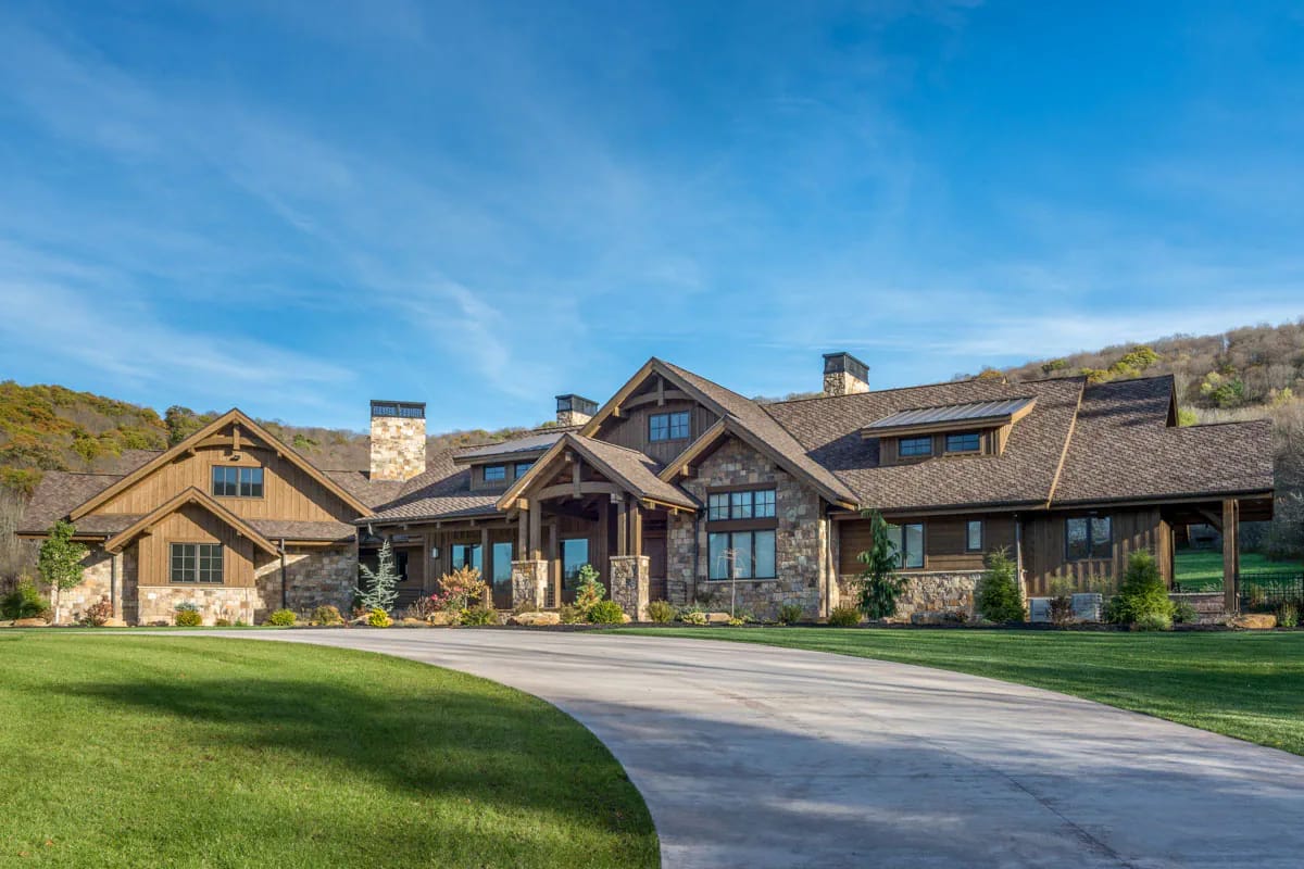 Rustic mountain-style home with stone and wood exterior, steep gables, and a large circular driveway.