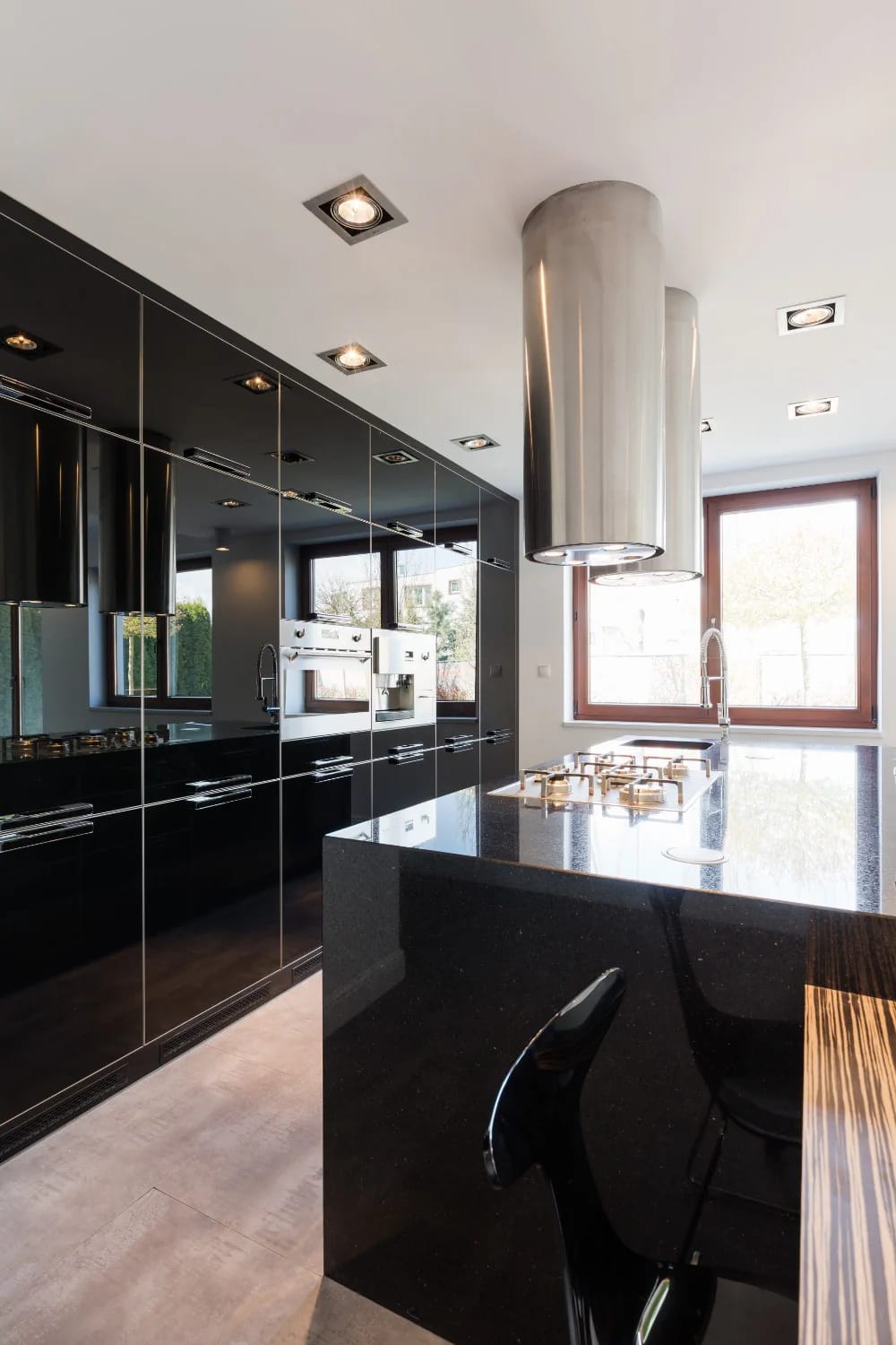 13 Kitchen Color Ideas and Where Each One Actually Works 16 Modern kitchen featuring glossy black cabinets, black countertops, stainless steel appliances, and large windows, illustrating kitchen color ideas where cabinets carry the color.