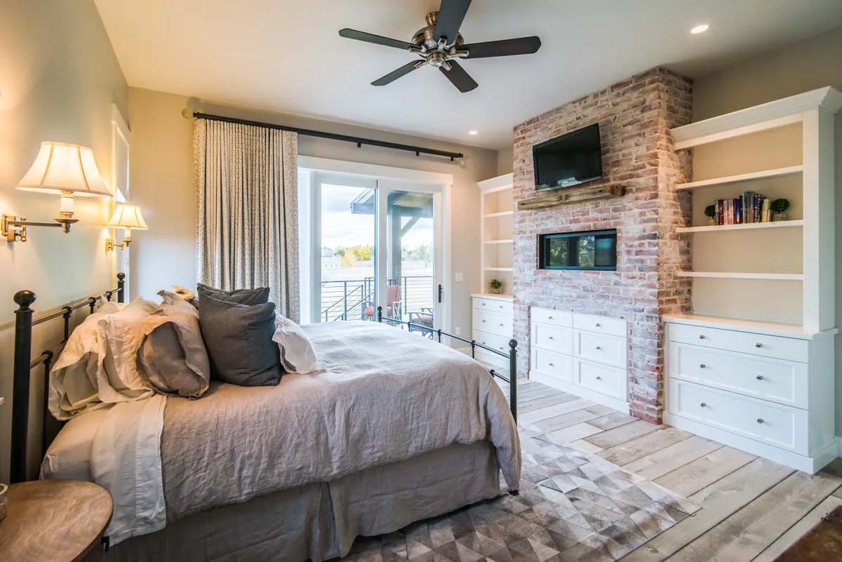 Bedroom with brick fireplace, built-in cabinets, and sliding doors to balcony
