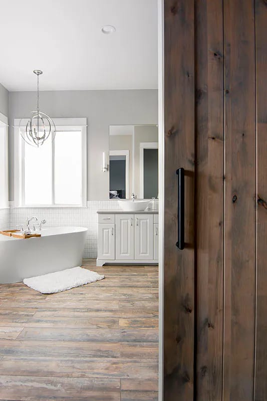 Bright bathroom with soaking tub, wood barn door, and double vanity in modern farmhouse style