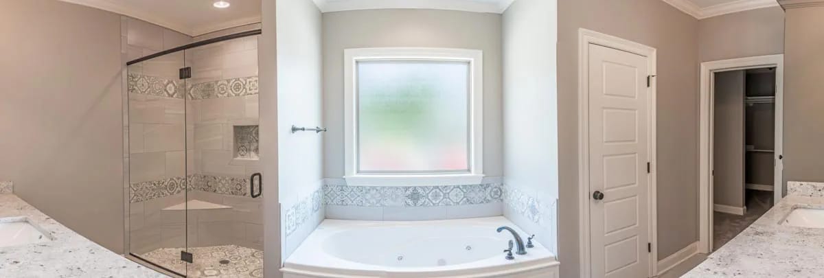 Bright bathroom with tiled glass shower, built-in tub, patterned tile accents, and adjacent walk-in closet
