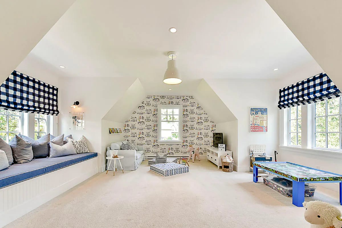 Bright children's playroom with sloped ceiling, window seat, and playful wallpaper accent wall