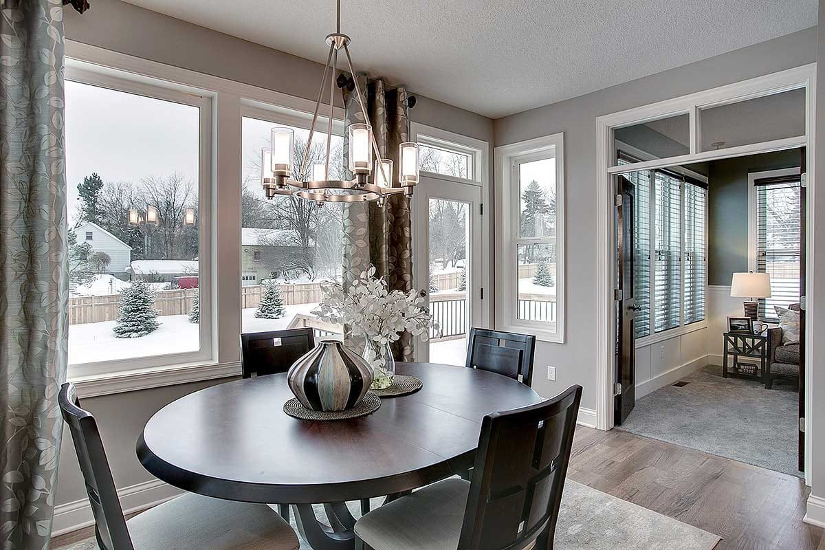 Bright dining nook with dark wood table, large windows, and modern chandelier