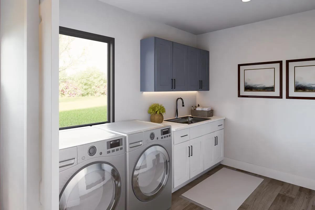 Bright laundry room with blue-gray cabinets, white counters, washer and dryer, and a large window