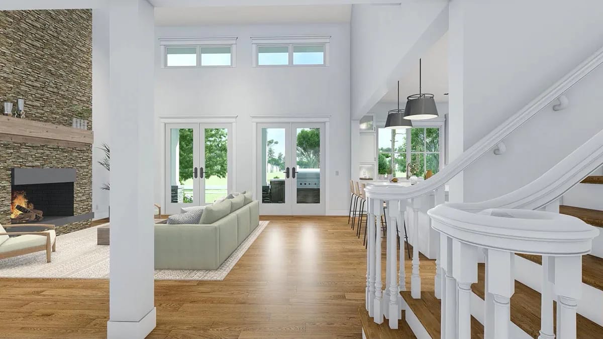 Bright open living room with stone fireplace, double-height windows, white staircase, and wood floors