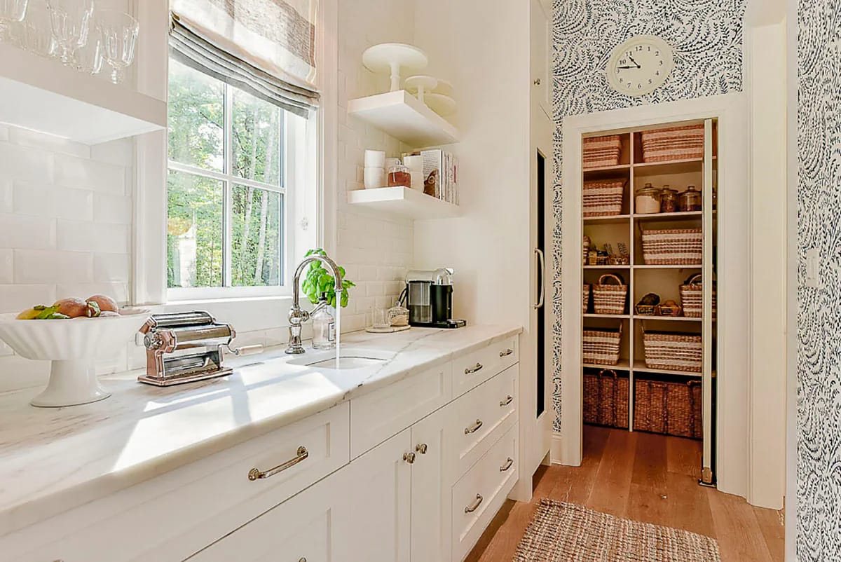 Bright pantry with white cabinets, marble counters, open shelves, and organized walk-in pantry.