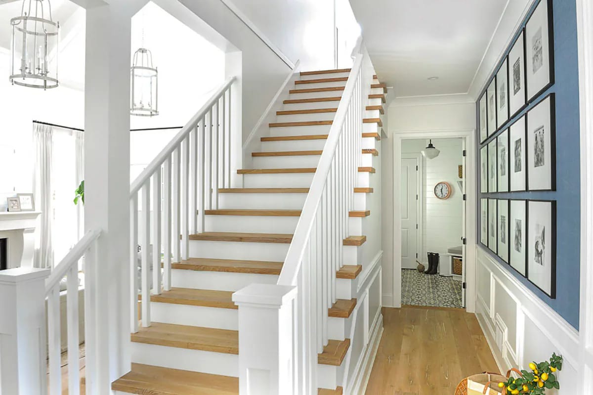 Bright stair hall with wood treads, blue gallery wall, and lantern pendant lights