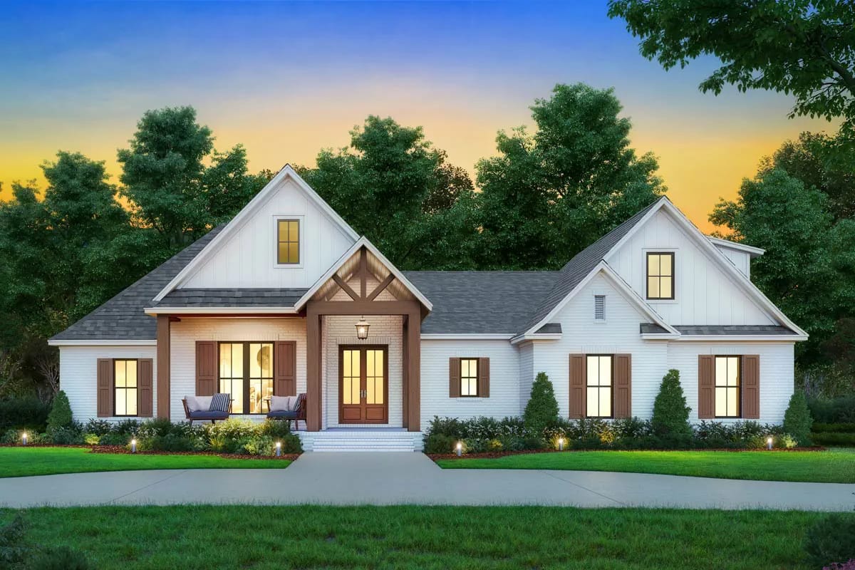 Cottage-style white home with gabled rooflines, covered entry porch, warm windows, and landscaped front walk at dusk