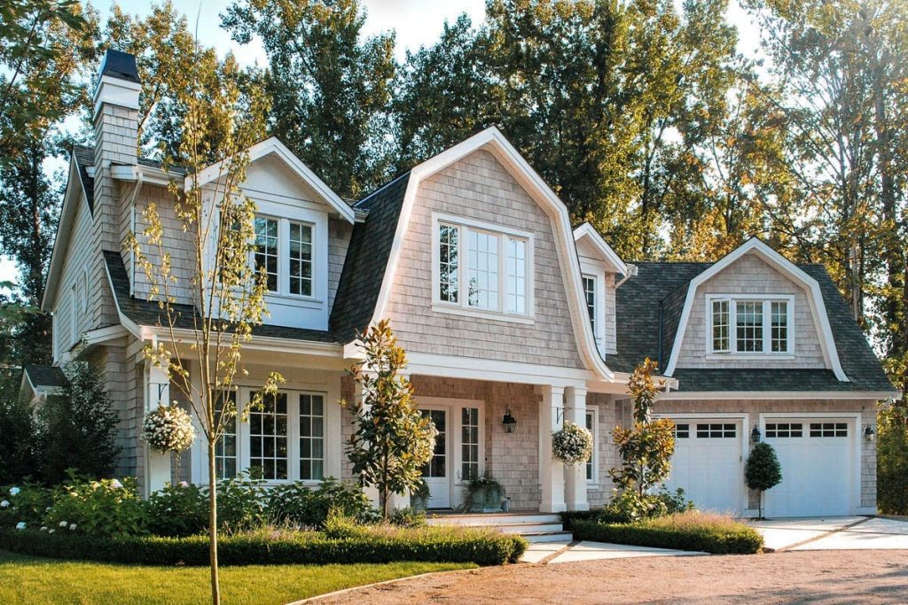 Dutch Colonial style home with gambrel roof, shingle siding, and a welcoming front porch