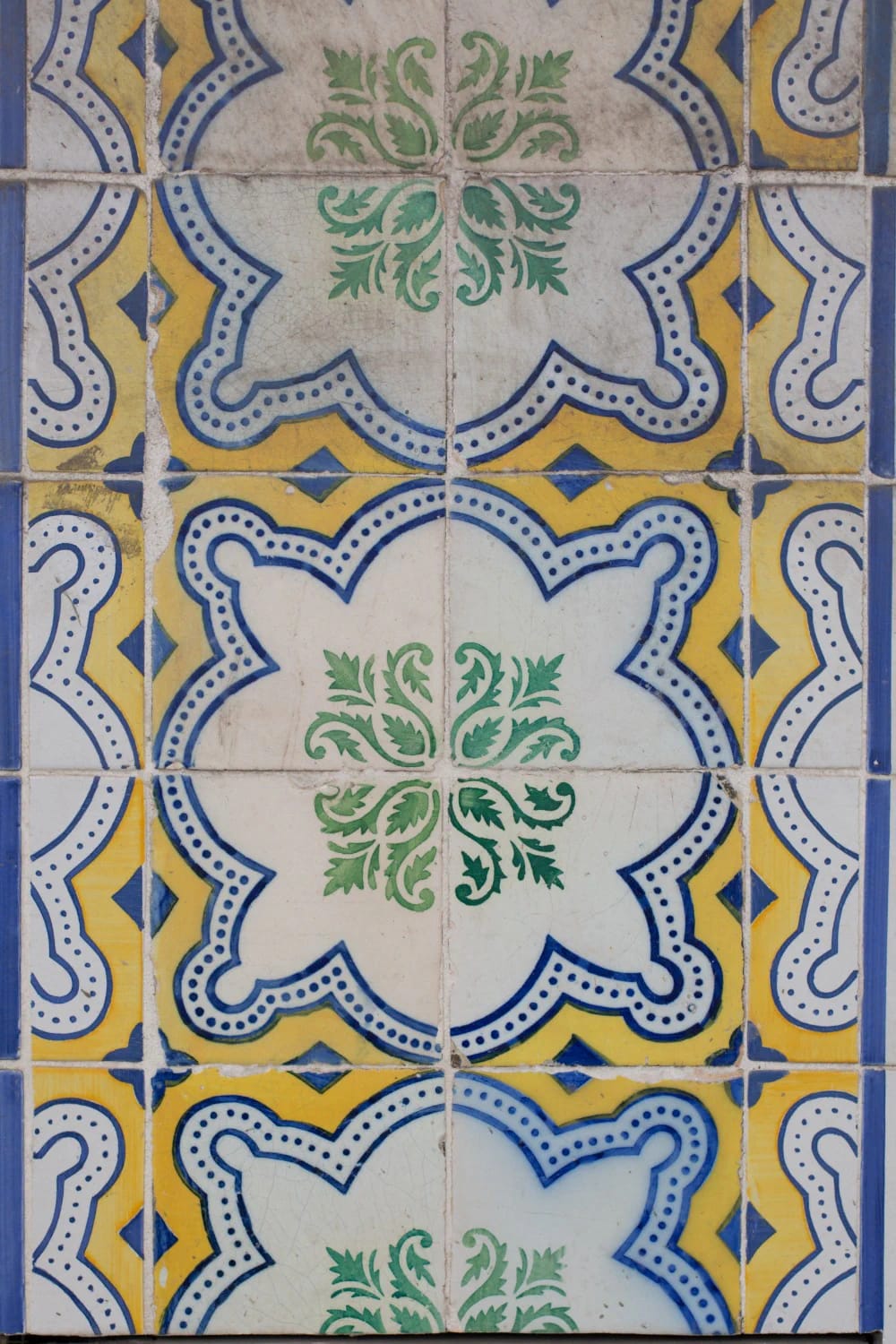 Close-up of patterned backsplash tiles featuring repeating white, blue, yellow, and green ornamental motifs for an eclectic kitchen design